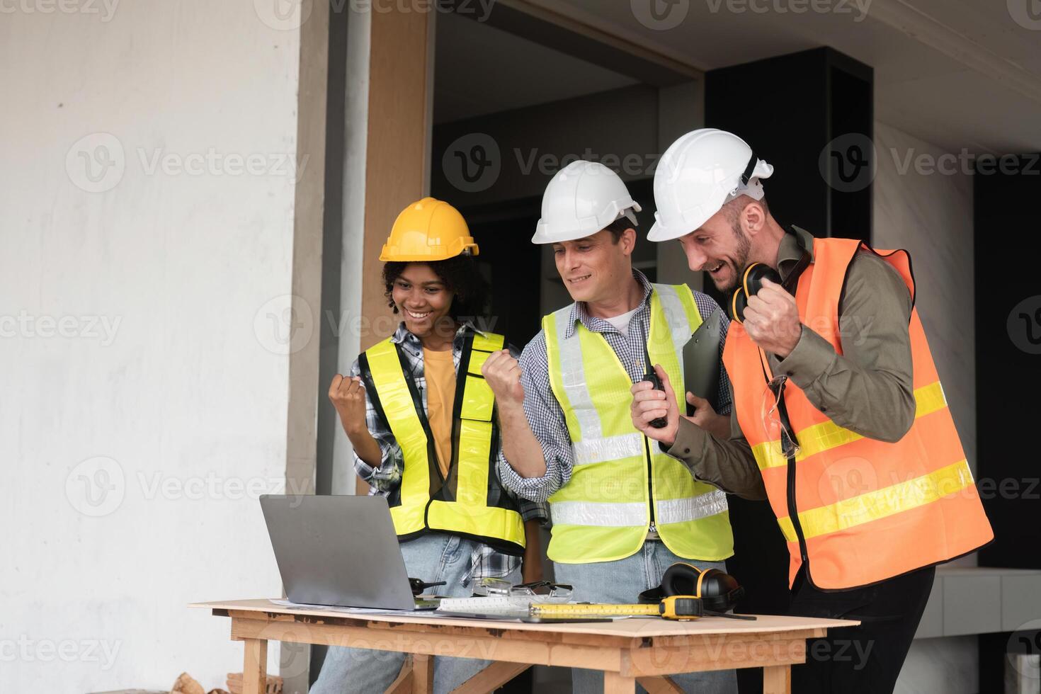 Engineering Team Collaborates on Work Plan at Construction Site with Laptops and Safety Gear photo