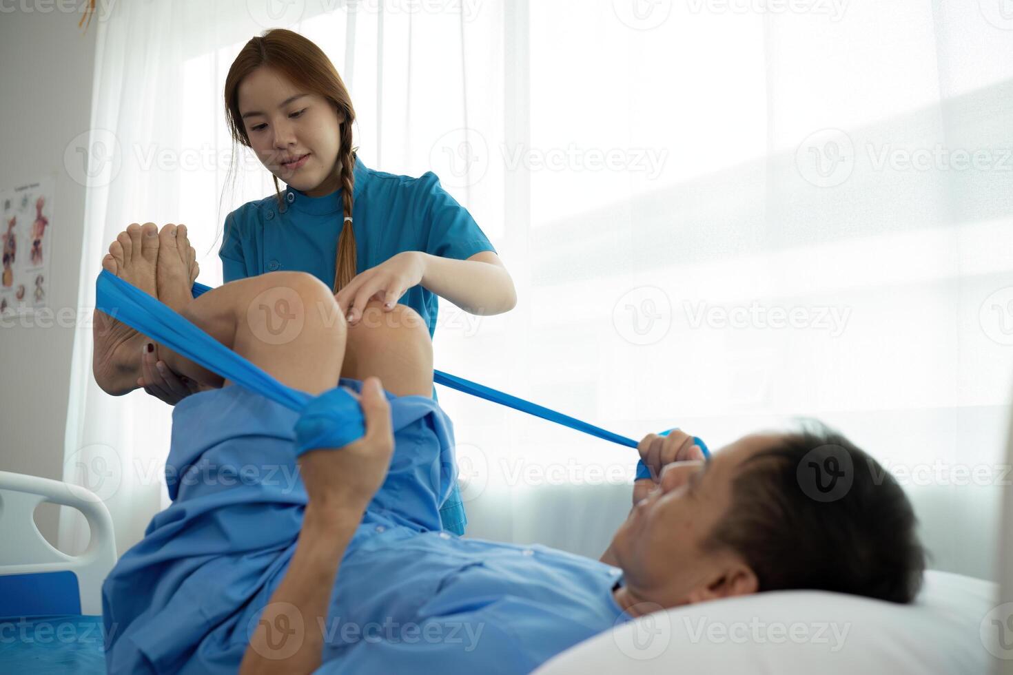 a woman in a blue uniform helps a man in a hospital bed photo