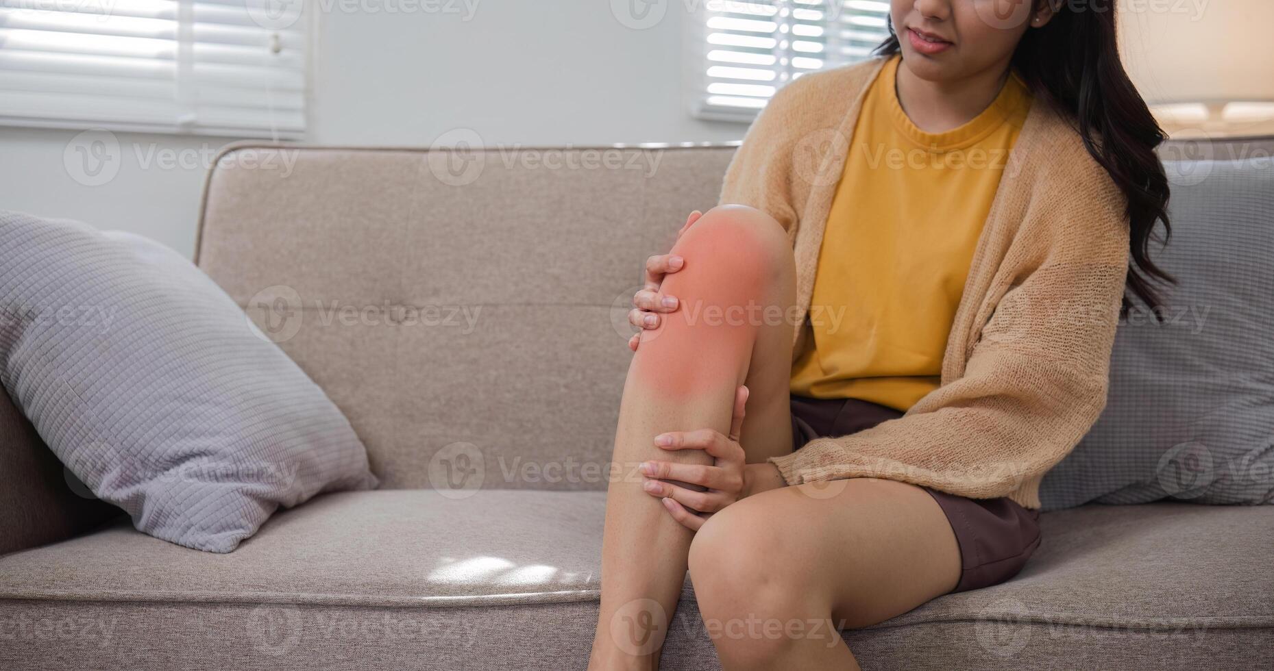 Woman Experiencing Knee Pain While Sitting on Couch at Home - Health and Wellness Concept photo