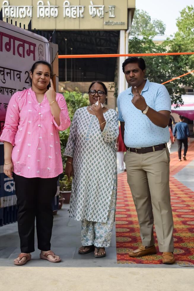 New Delhi, India - May 25 2024 - Unidentified people showing their ink-marked fingers after casting votes in front of polling booth of east Delhi area for general Lok Sabha Elections 2024 photo