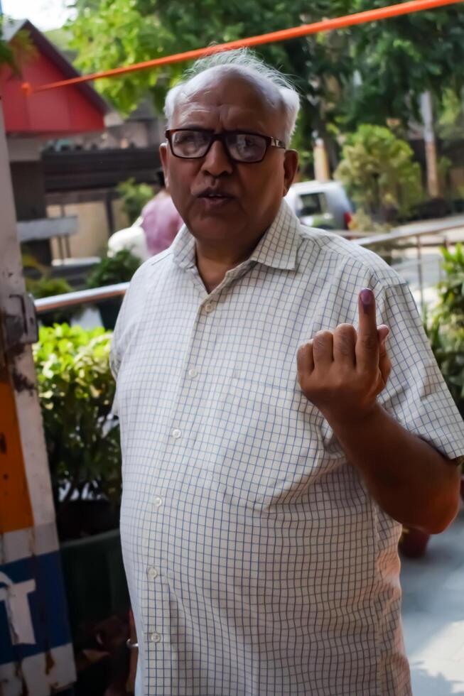 New Delhi, India - May 25 2024 - Unidentified people showing their ink-marked fingers after casting votes in front of polling booth of east Delhi area for general Lok Sabha Elections 2024 photo