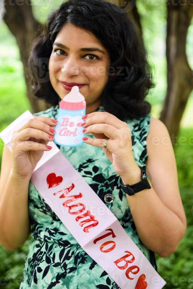 A pregnant Indian lady poses for outdoor pregnancy shoot and hands on belly, Indian pregnant woman puts her hand on her stomach with a maternity dress at society park, Pregnant outside maternity shoot photo