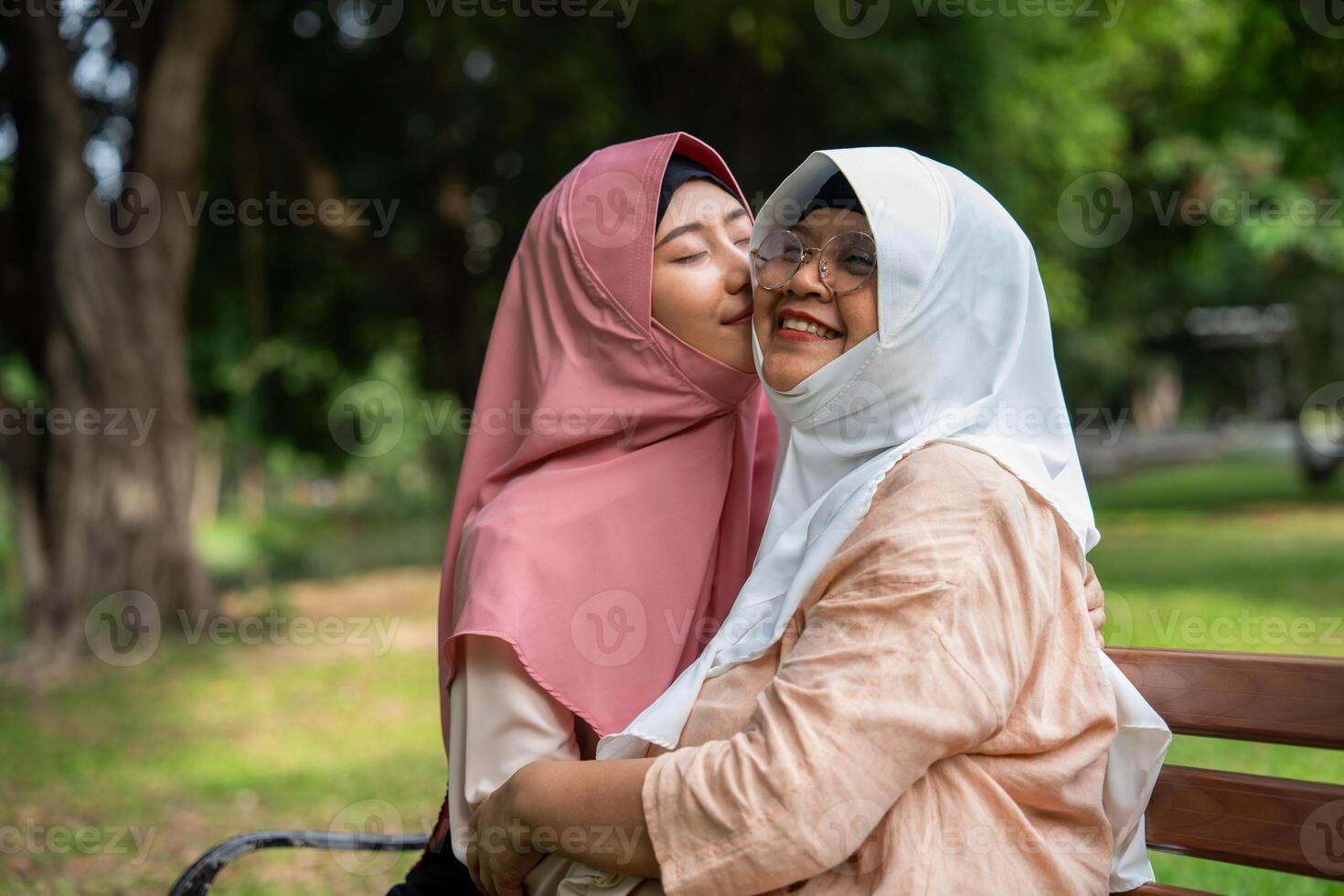 Muslim careful caregiver or nurse taking care of the patient in the hospital park. Happy Muslim mother in hijab hugging daughter. Concept of Savings and Senior Health Insurance, a Happy Family photo