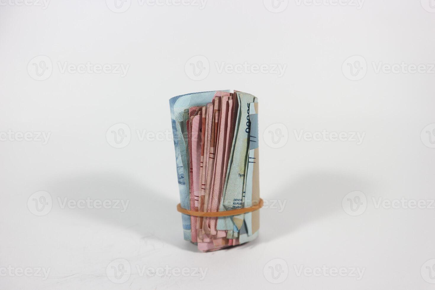 A packet of several rupiah bills is folded in half and tied with a rubber band. Bundle isolated on white background with clipping path. photo