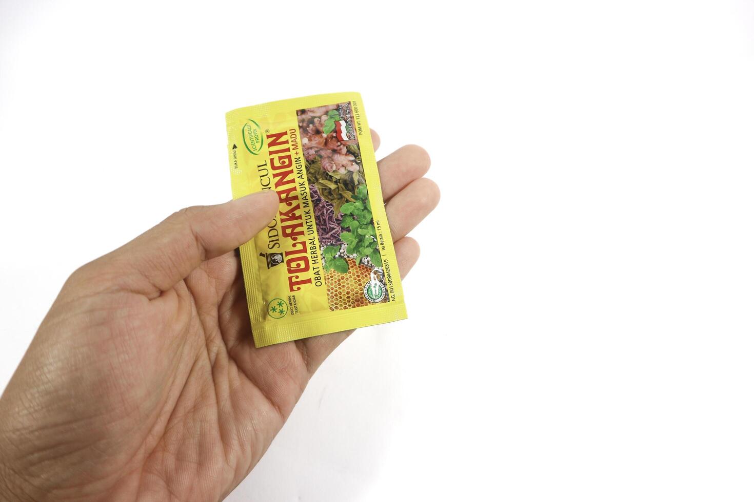 Lampung, Indonesia - 08th July 2024 A hand holding Tolak Angin, showcasing the popular Indonesian herbal remedy for cold and immune support. isolated on white background photo