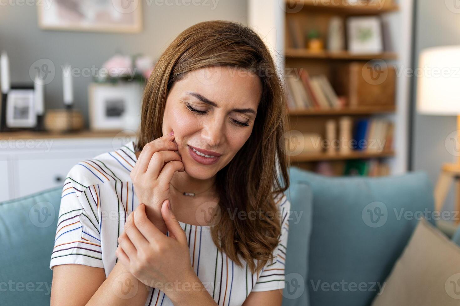 Portrait of unhappy young woman suffering from toothache at home. Healthcare, dental health and problem concept. photo