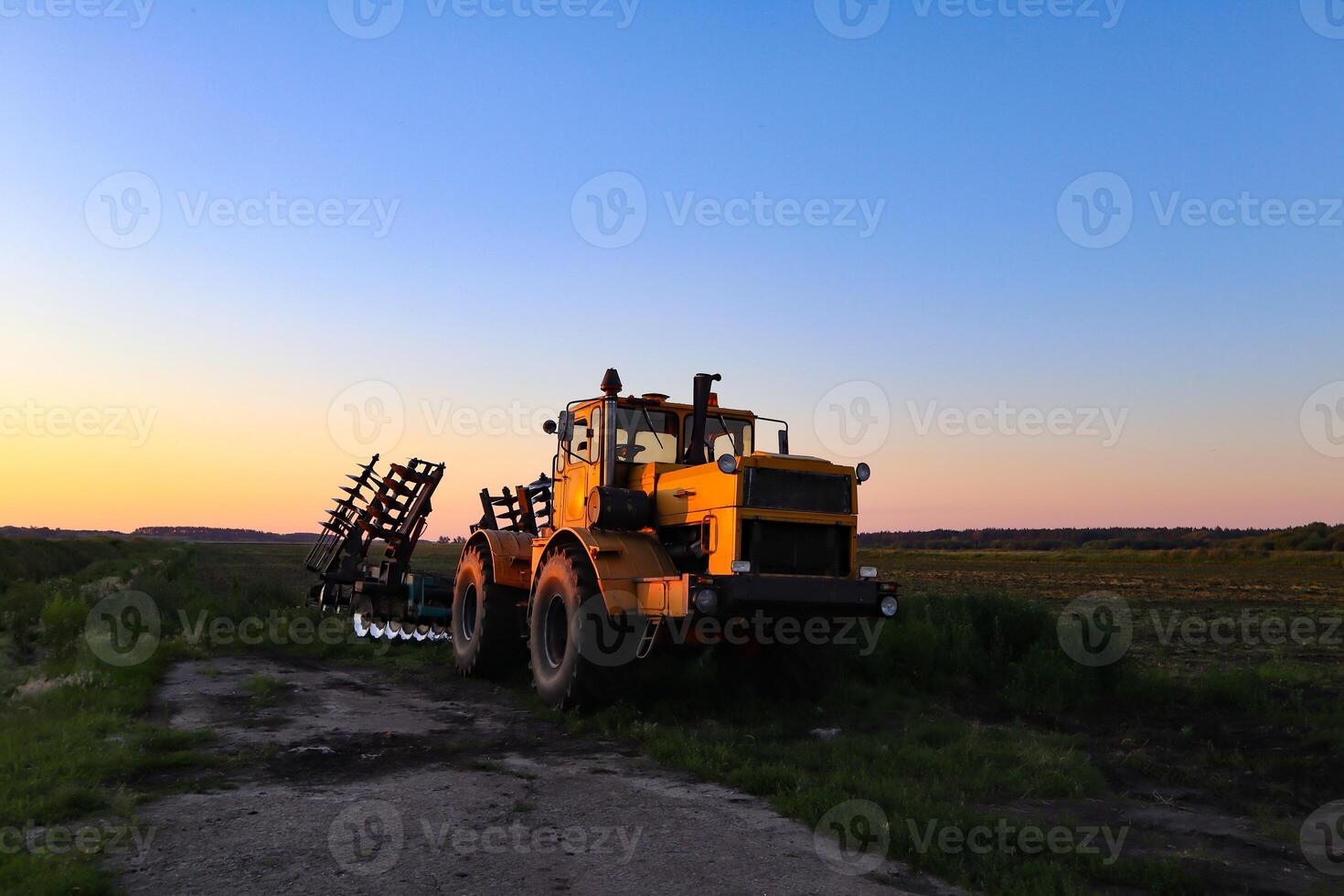 Cultivator on agricultural field at golden hour. Machine in field at sunset. photo
