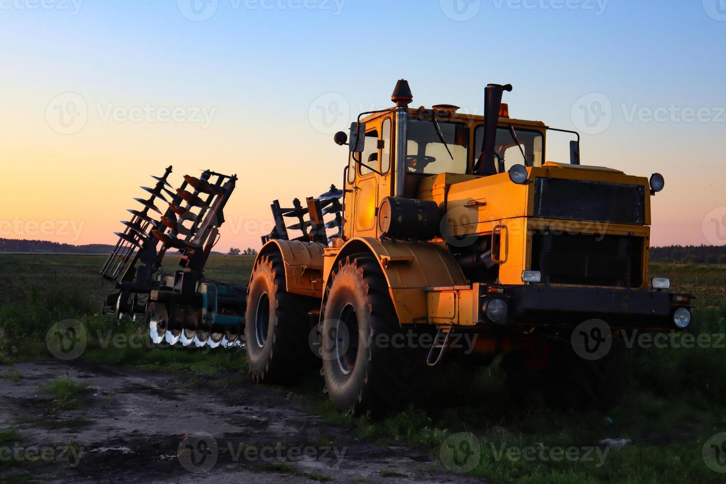 Cultivator on agricultural field at golden hour. Machine in field at sunset. photo