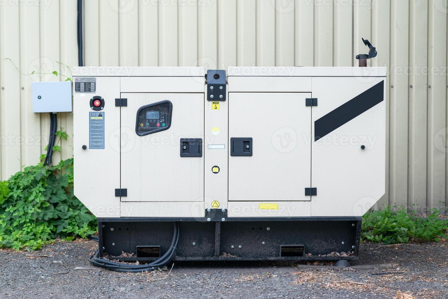 auxiliary diesel generator for emergency power supply. Industrial generator connected to the control panel by a cable wire. Backup power supply of the generator photo