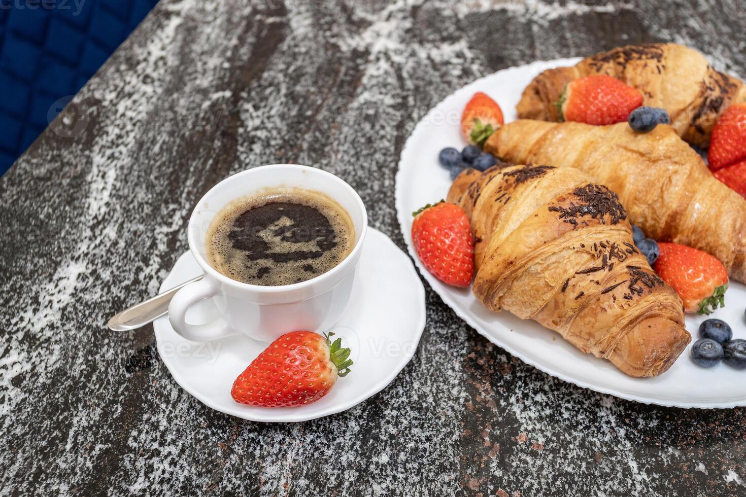 Checker of coffee with strawberries and pastries photo