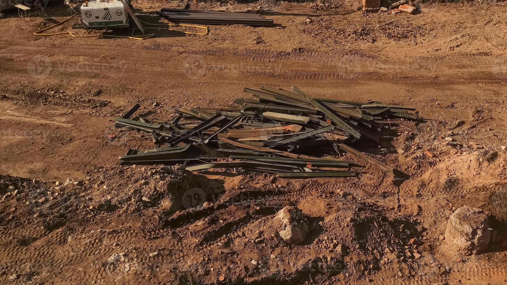 A pile of scrap metal sits on a dirt road at a construction site photo