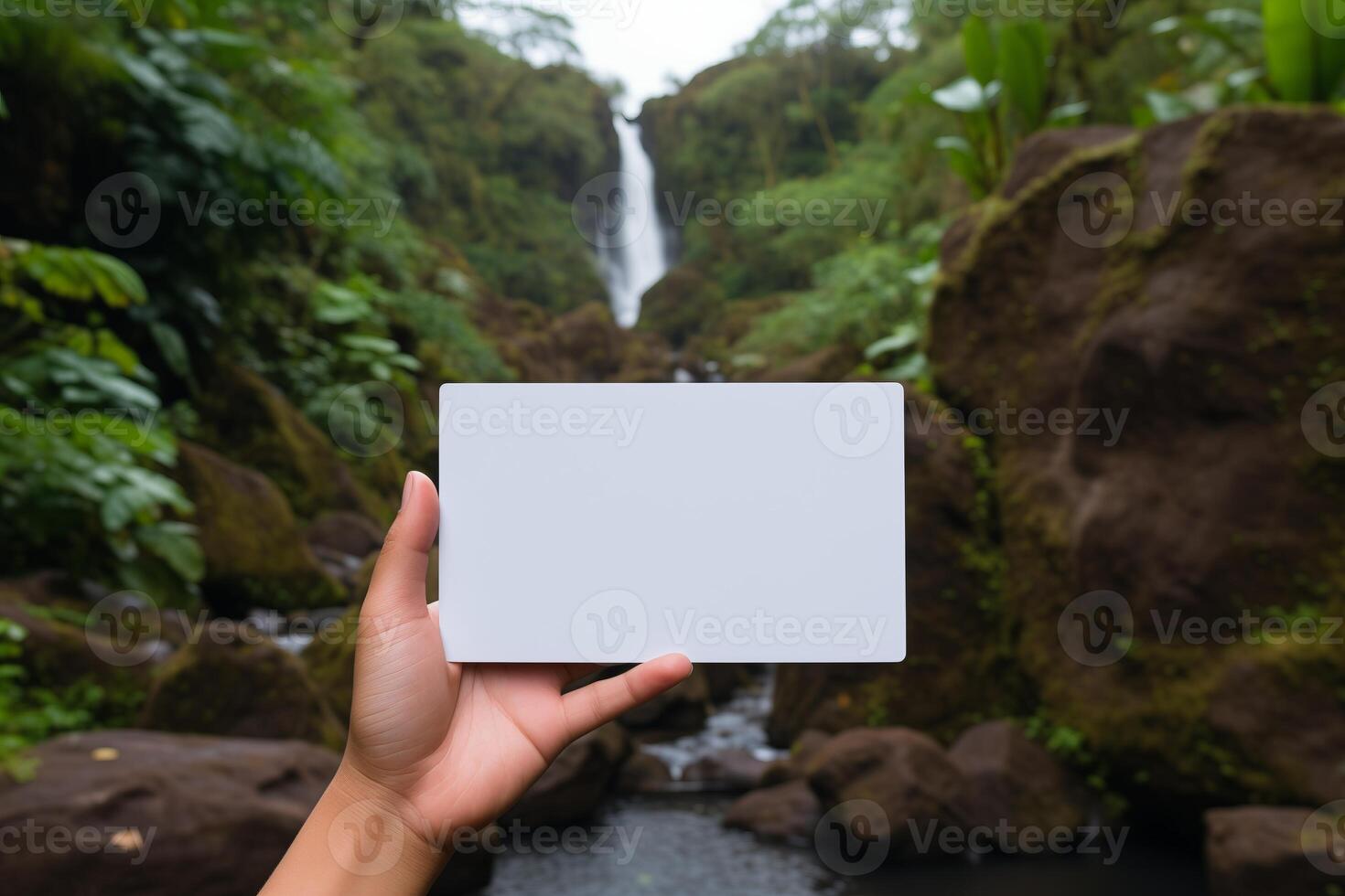 A person standing in front of a waterfall, holding a card in their hand. photo