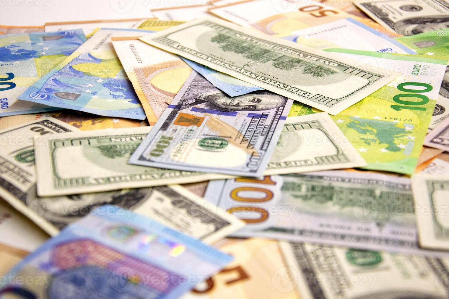 An assortment of US dollar and euro bills are scattered on a white surface photo