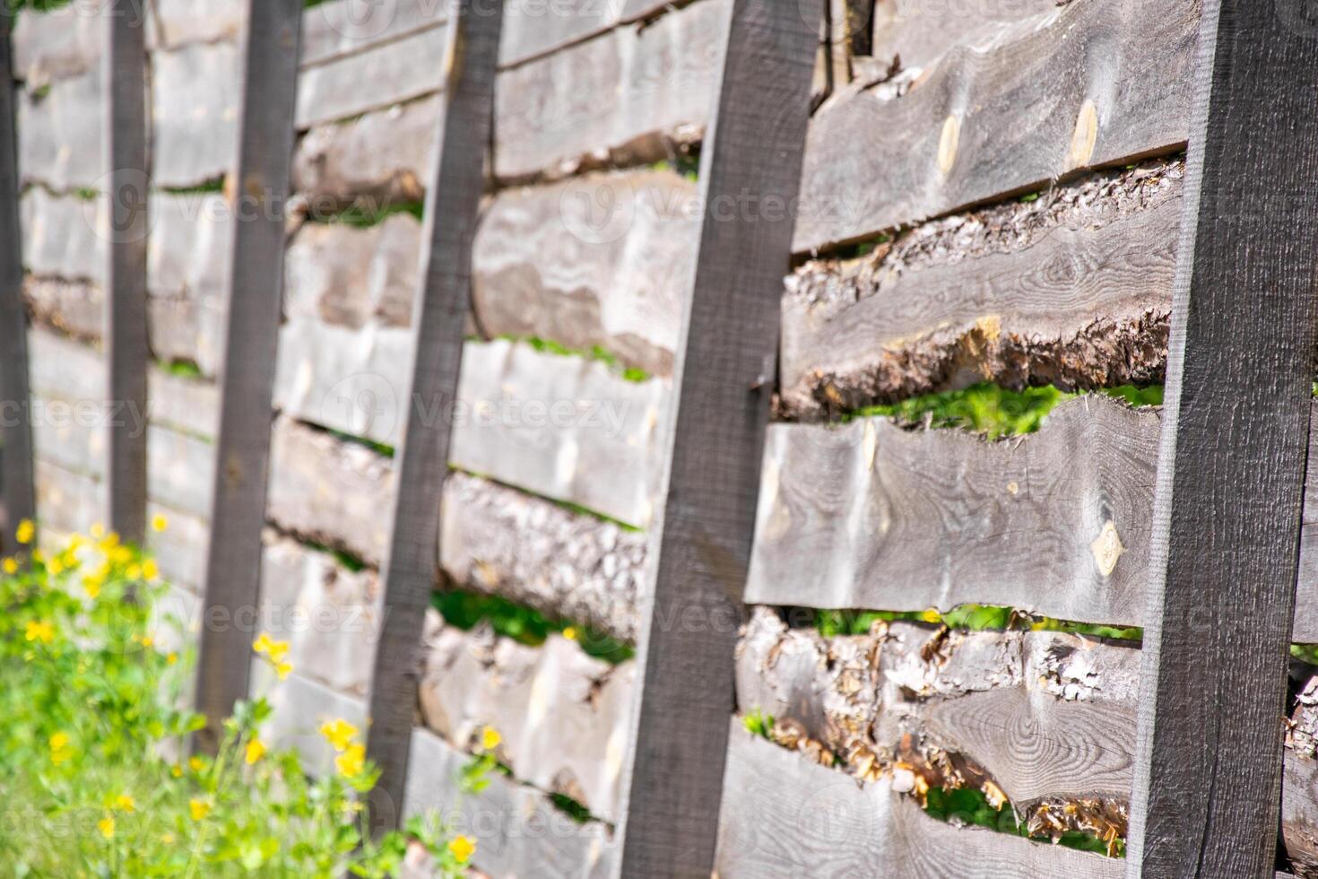 A close-up image showcasing a rustic wooden fence constructed with horizontal planks and sturdy black posts. The wood is weathered and aged, with visible signs of time and exposure to the elements photo