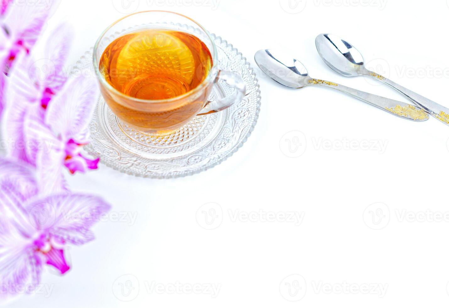 a transparent cup of aromatic tea and a pink orchid on a white background photo