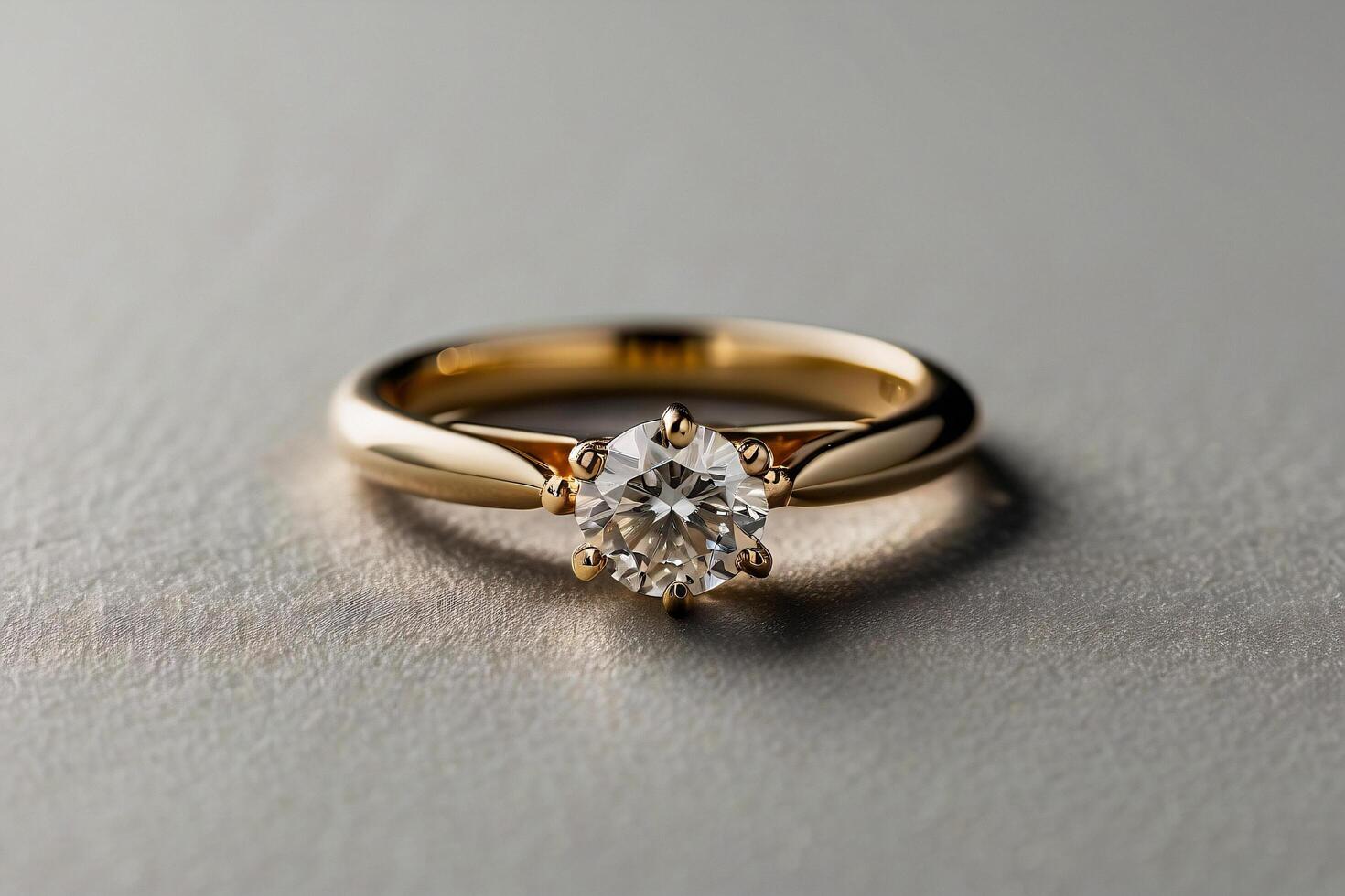 an elegant diamond engagement ring with a prominent solitaire, set on a slender gold band. The textured grey background adds a touch of sophistication photo