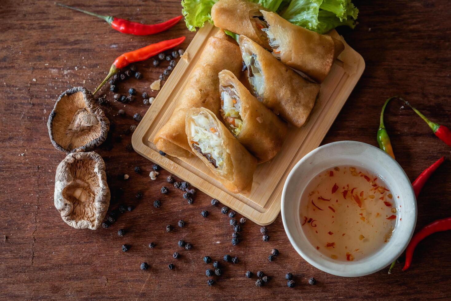 Chinese vegetable spring rolls with chopstick to dip in sauce on wooden background photo