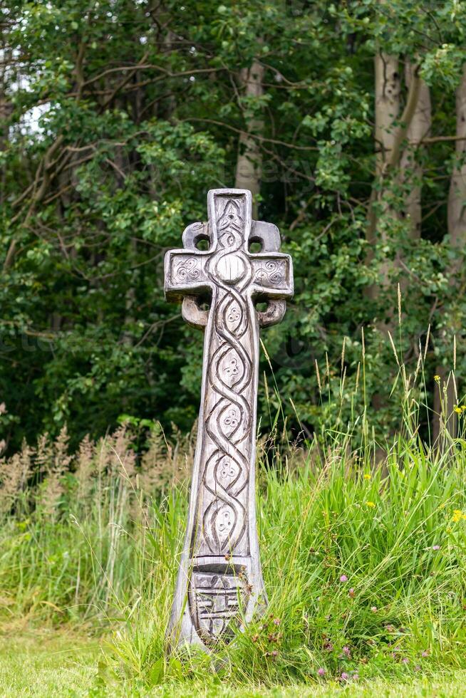 Celtic cross - a wooden cross in a meadow by the forest photo