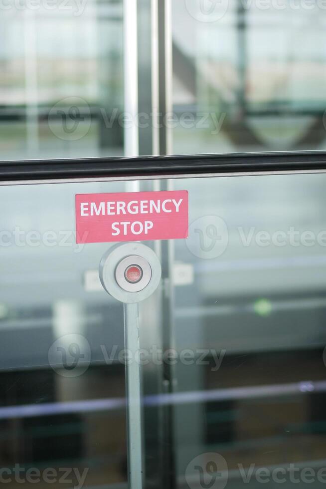 An emergency stop button is placed on a glass wall in a public space for safety measures photo