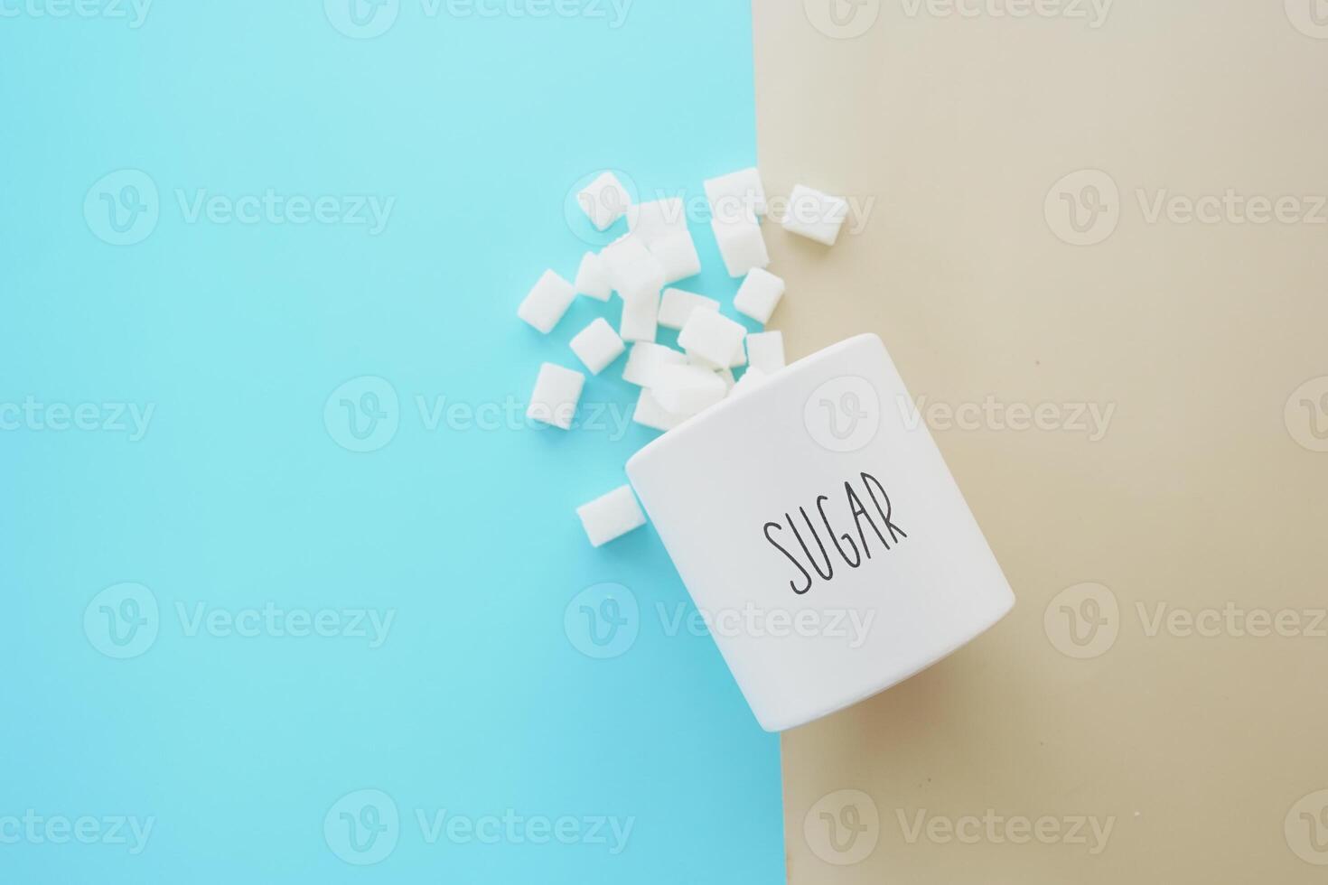 Sugar cubes are accidentally spilled from a container onto a background with two contrasting colors photo