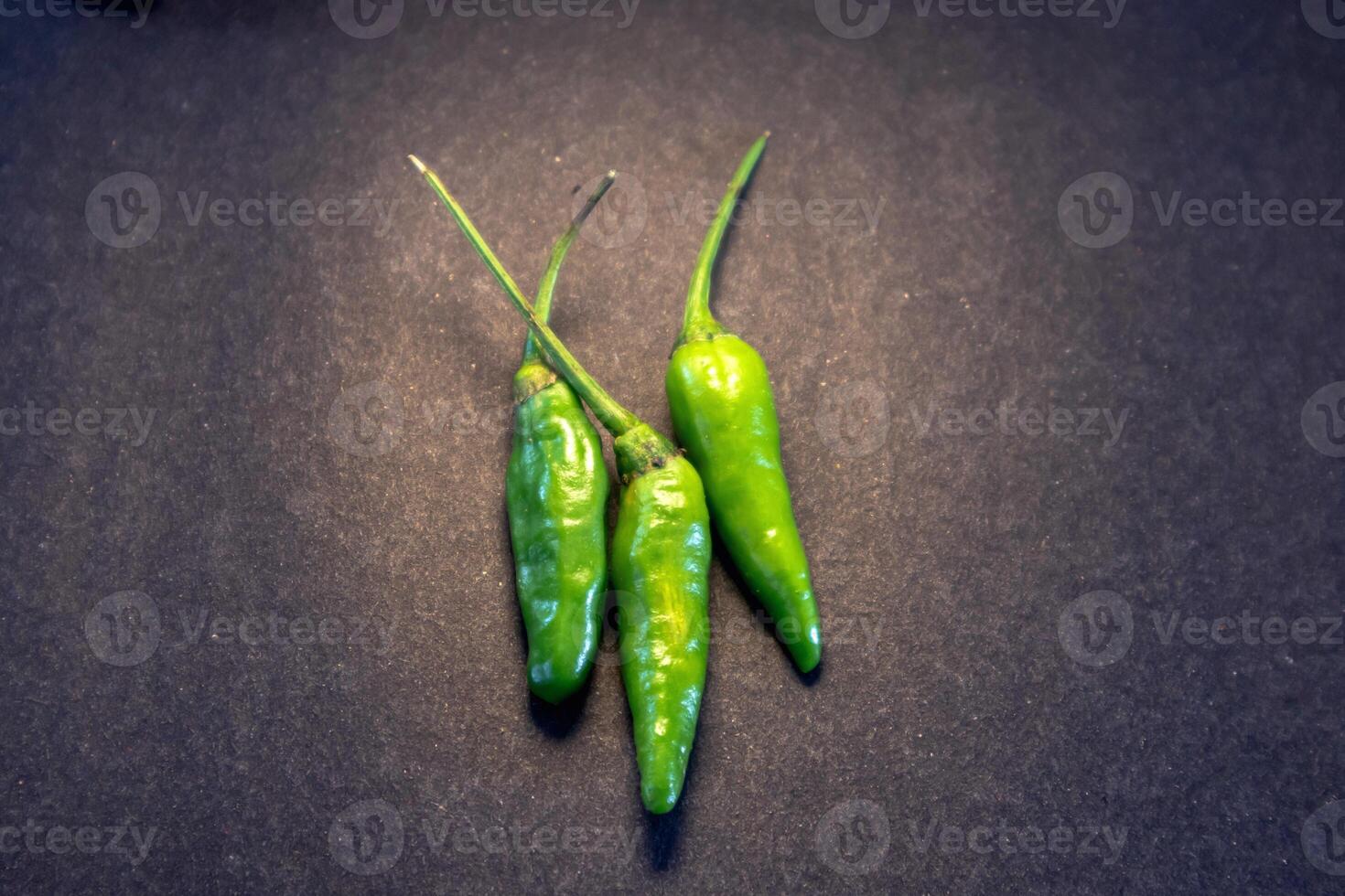 Three green cayenne pepper with very spicy taste isolated on dark background photo
