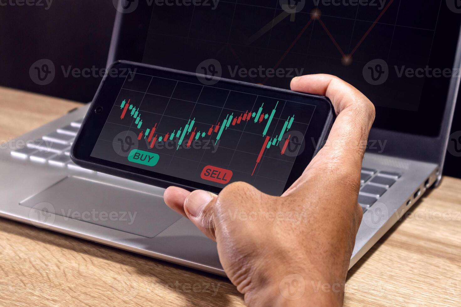 A man's hand using a smartphone to analyze stock market, cryptocurrency or trading data charts. Risk management in trading concept. photo
