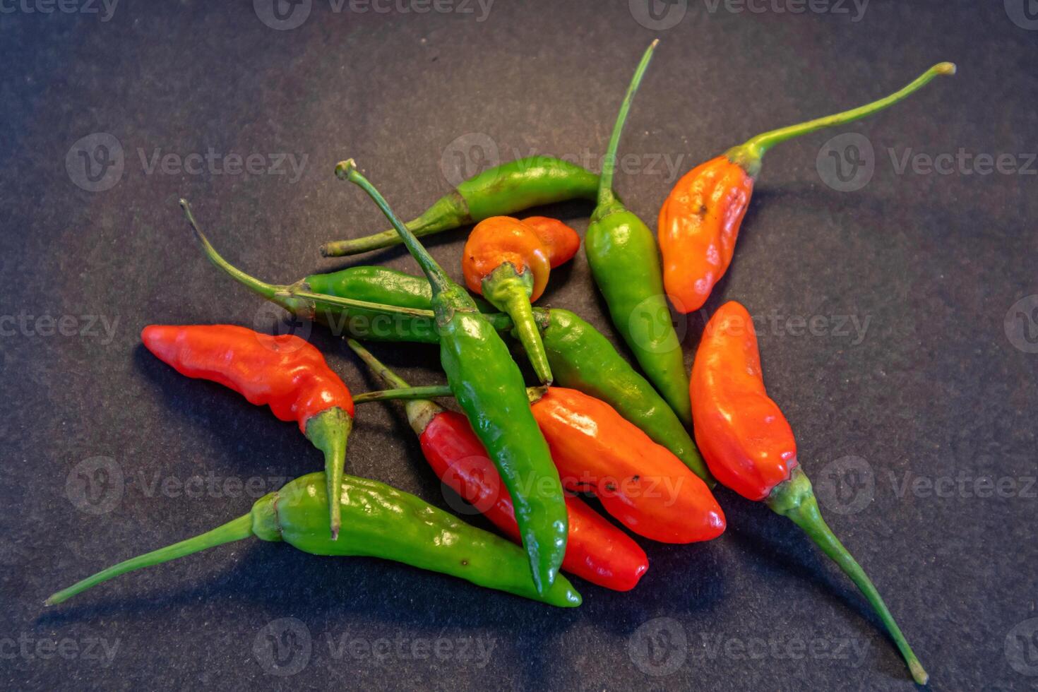 Pile of red and green cayenne pepper isolated on dark background photo