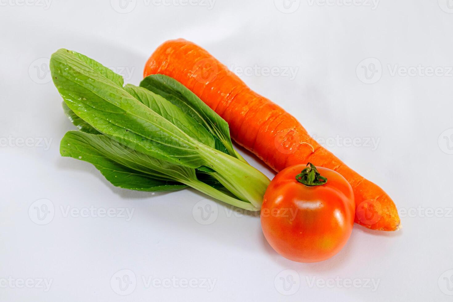 Fresh vegetables on white background. Carrot, tomato, and pak choi cabbage. photo
