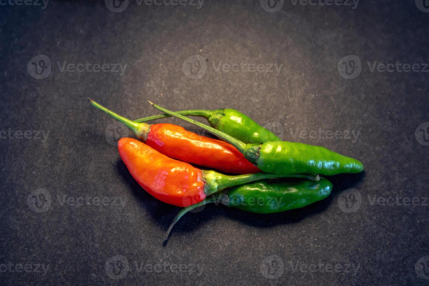 Pile of red and green cayenne pepper isolated on dark background photo
