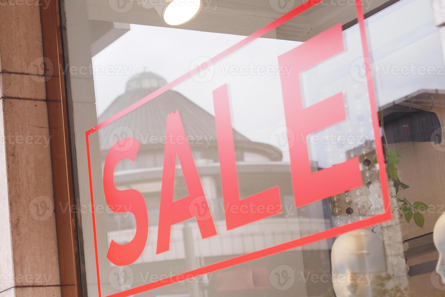 Large red Sale text letters on a glass wall obstruct a view inside the popular fashion store photo
