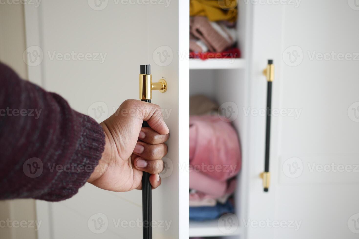 The closet has efficiently arranged shelves with neatly folded clothes when opened photo