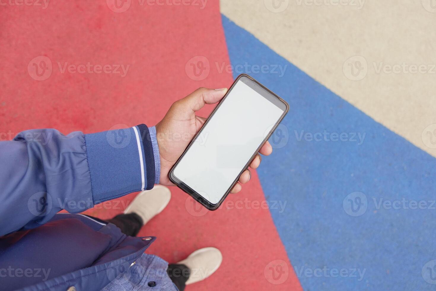 A person is holding a smartphone with a blank screen against a colorful background photo