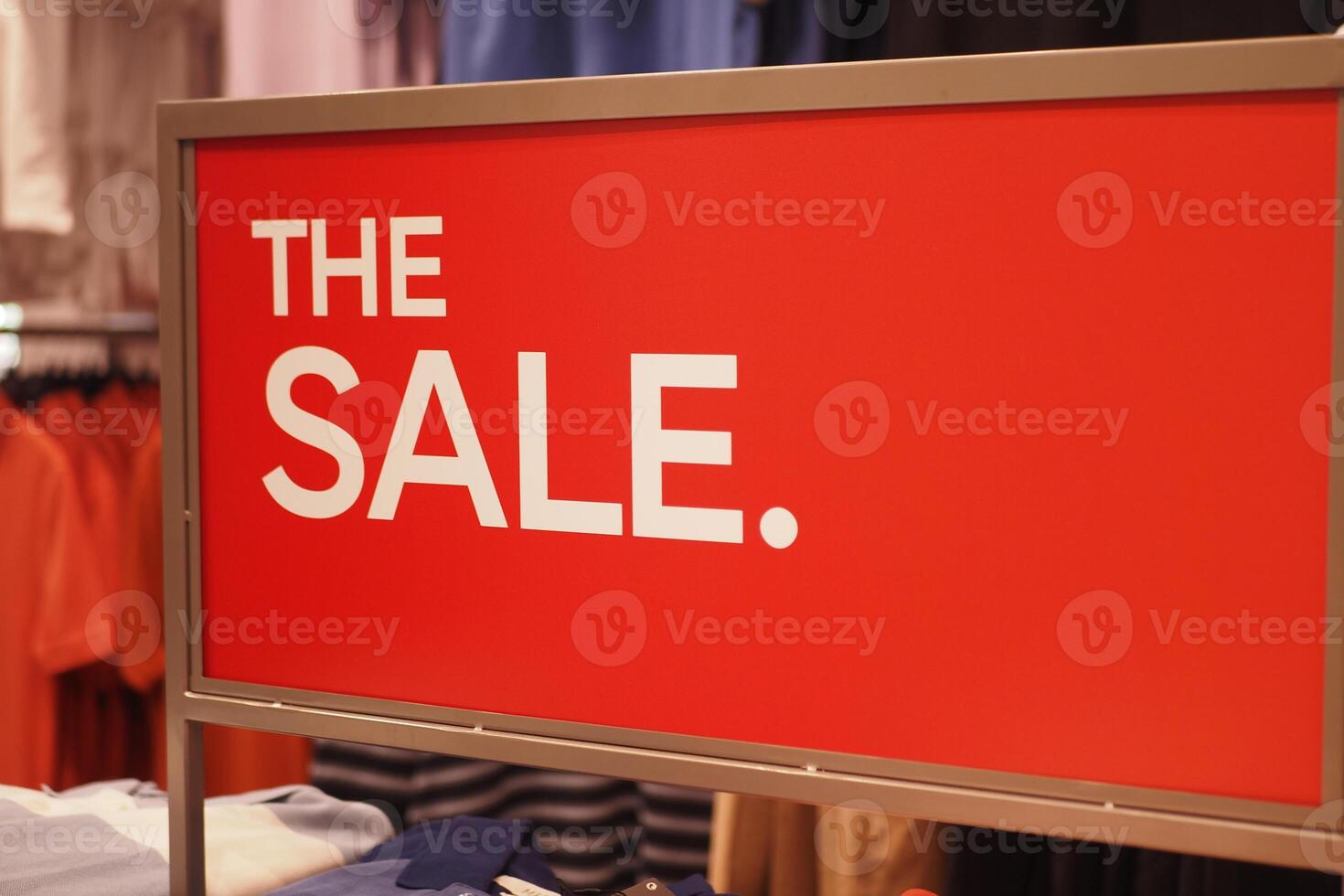 Red Sale Sign in Clothing Store Featuring Large Bold Text on Promotional Board photo