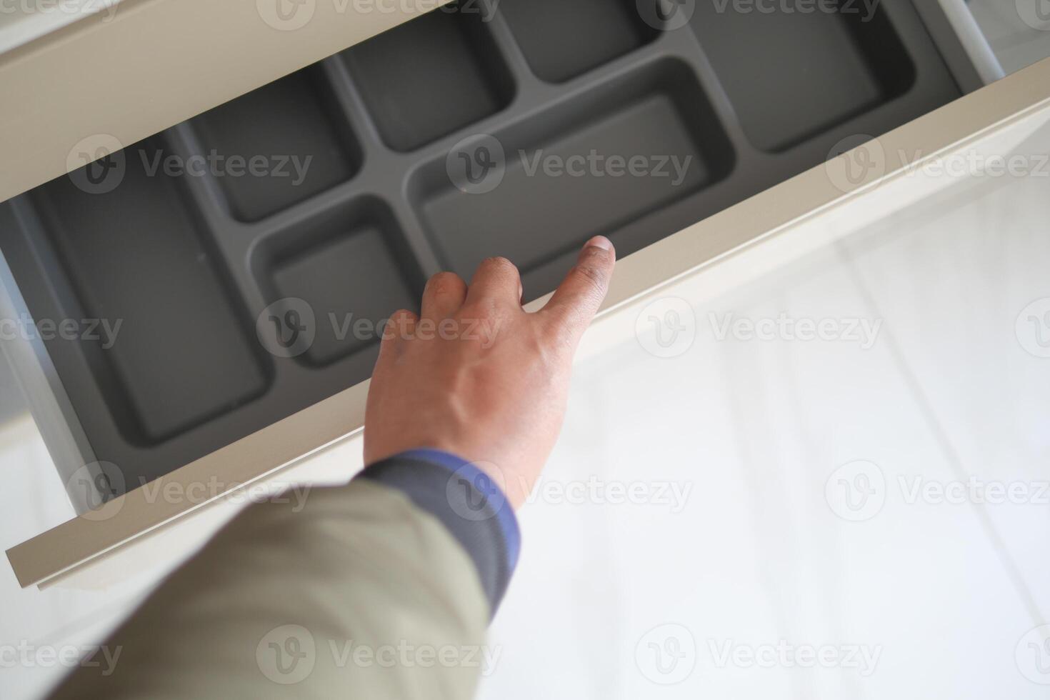 Hand opens drawer with empty organizing tray to maintain neat order in the space photo