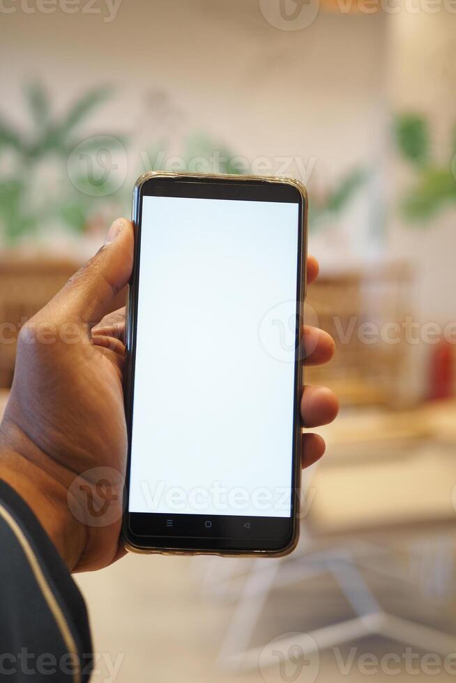 young man hand using smart phone with green screen at cafe photo