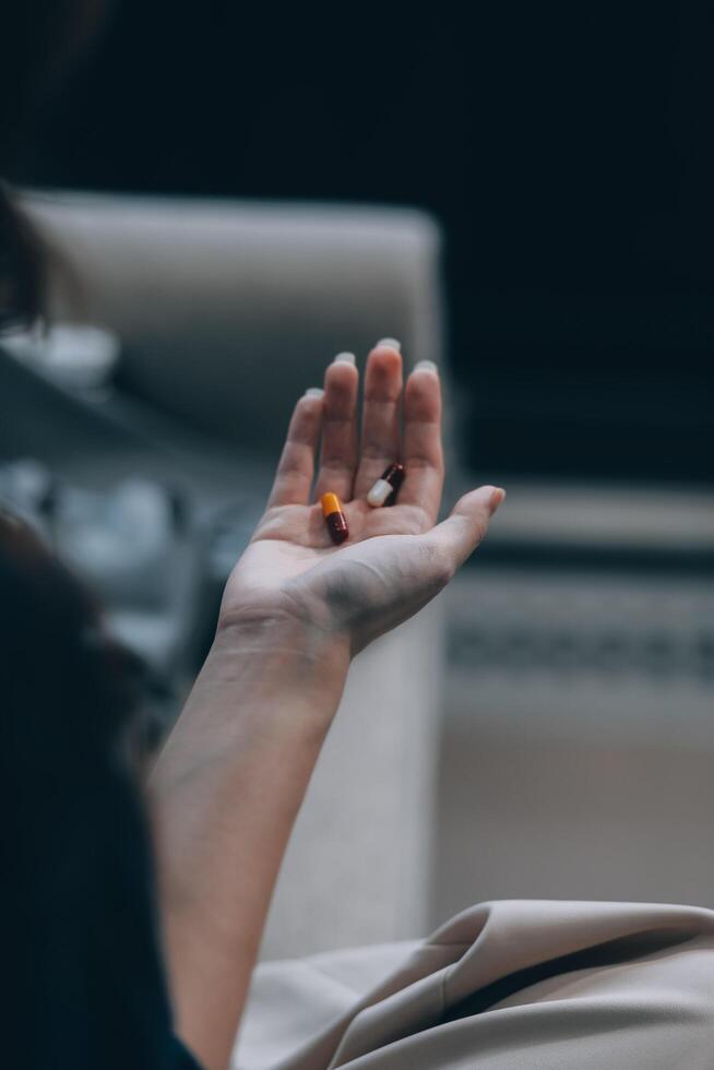A woman with a cold with pills is treated at home chooses which drugs to take and self-medicates, checks the expiration date while sitting on the couch at home photo