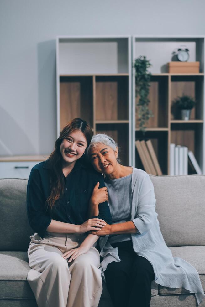 Adult daughter old mom hugging sit on couch enjoy pleasant positive talk, remembering funny occasion from life spend weekend together, caring about older generation relatives express attention concept photo