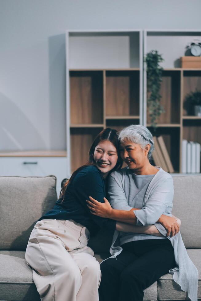 Adult daughter old mom hugging sit on couch enjoy pleasant positive talk, remembering funny occasion from life spend weekend together, caring about older generation relatives express attention concept photo