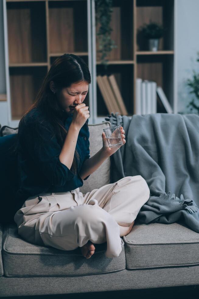 A woman with a cold with pills is treated at home chooses which drugs to take and self-medicates, checks the expiration date while sitting on the couch at home photo