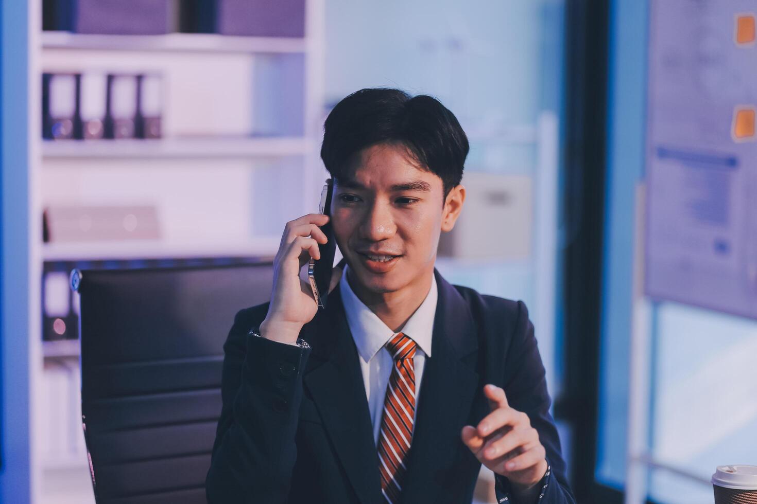 Serious trader using mobile phone app on smartphone for checking stock trading data analysis concept, focused businessman holding cellphone working in office with financial graph on computer monitors photo