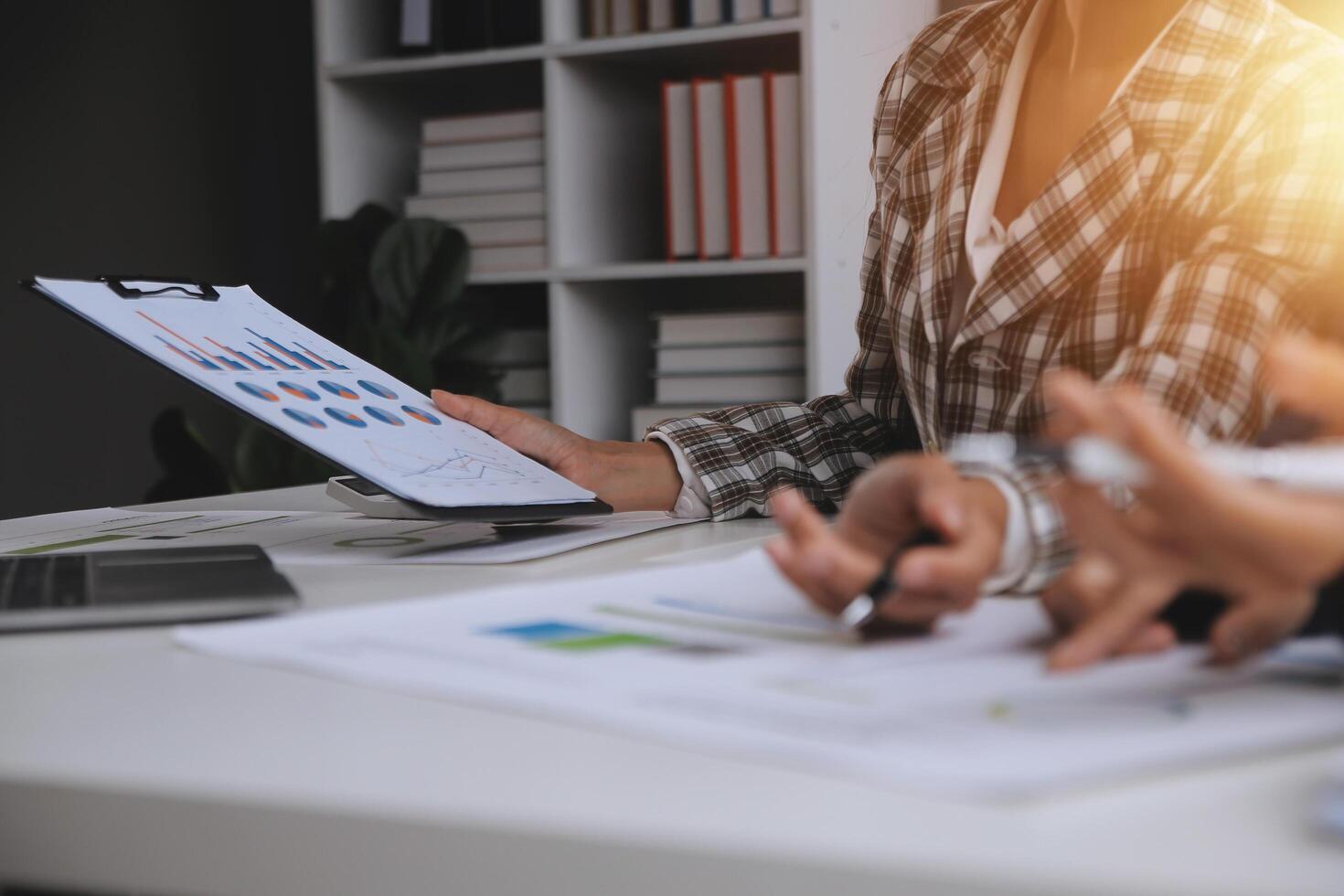 Group of confident business people point to graphs and charts to analyze market data, balance sheet, account, net profit to plan new sales strategies to increase production capacity. photo