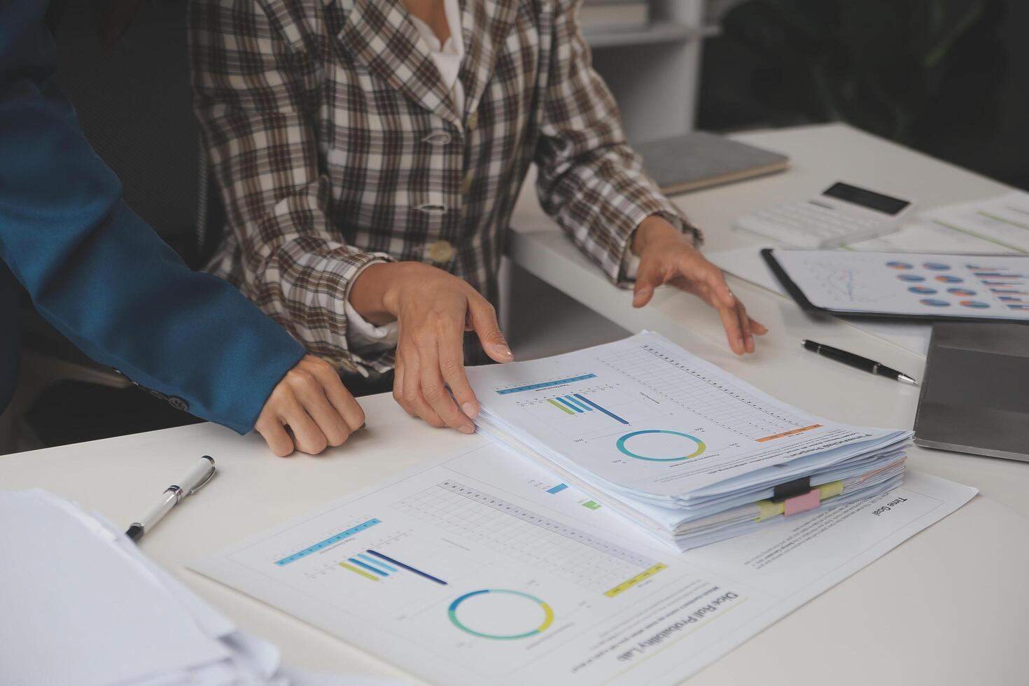 Group of confident business people point to graphs and charts to analyze market data, balance sheet, account, net profit to plan new sales strategies to increase production capacity. photo