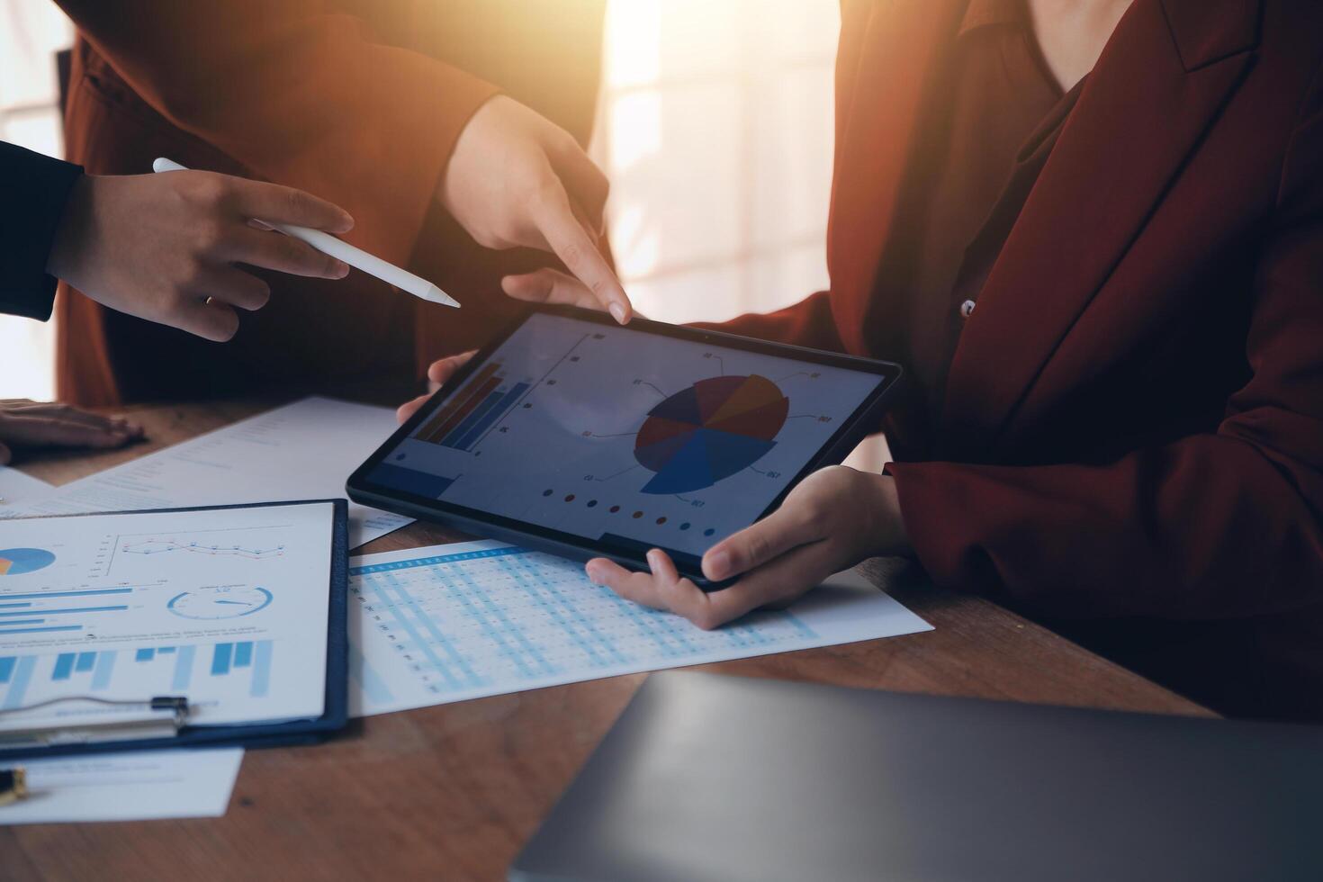 Group of confident business people point to graphs and charts to analyze market data, balance sheet, account, net profit to plan new sales strategies to increase production capacity. photo