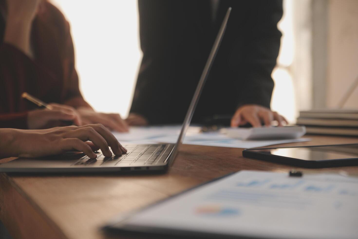 Group of confident business people point to graphs and charts to analyze market data, balance sheet, account, net profit to plan new sales strategies to increase production capacity. photo