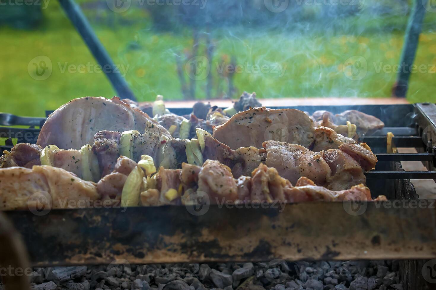 Cooking kebabs on a grill with smoke. Fresh brown BBQ meat cooked on an outdoor grill photo