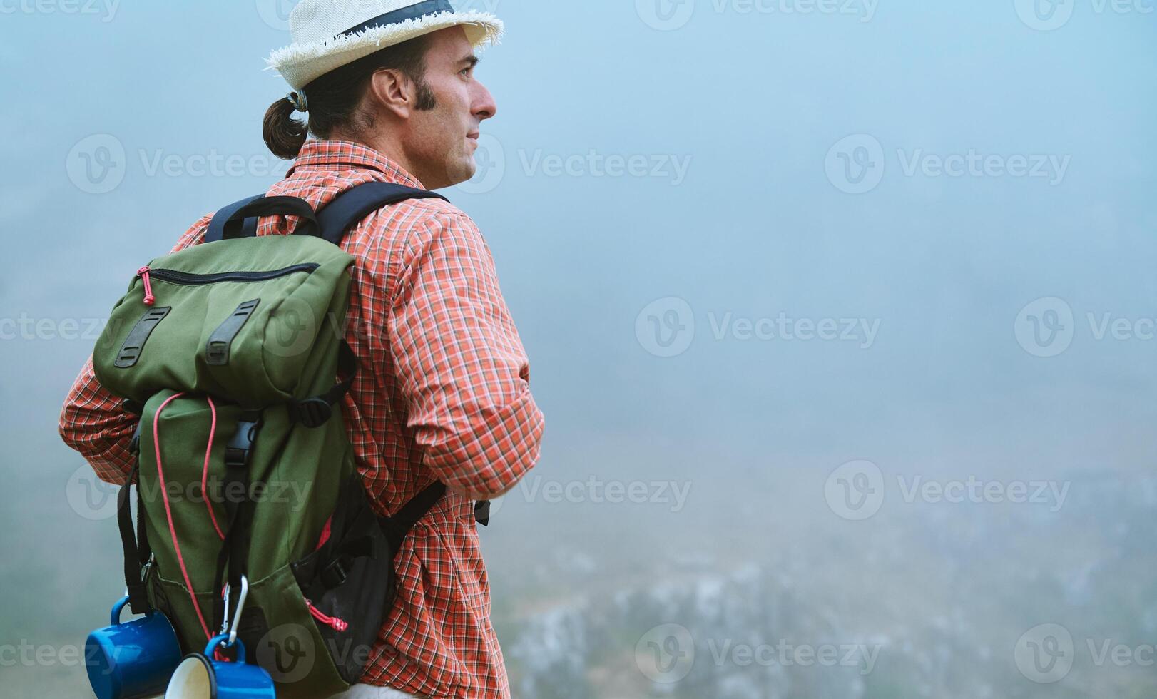 Man with backpack exploring foggy mountain landscape, embracing adventure in nature photo