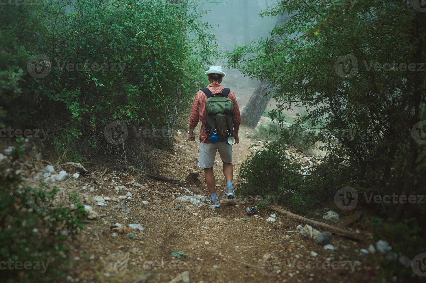 Man hiking on a foggy forest trail with a backpack in wilderness photo