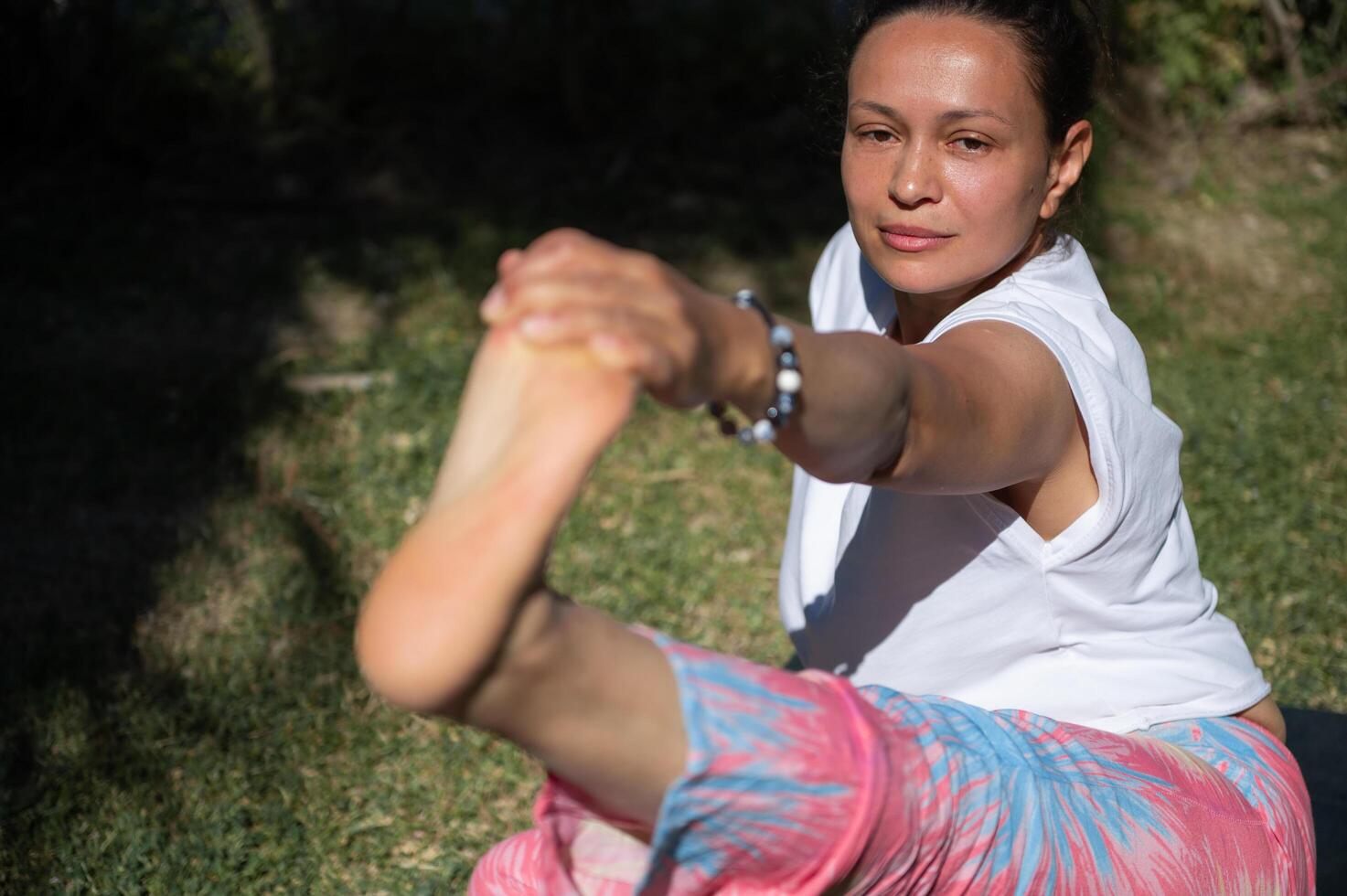 Woman practicing yoga outdoors, stretching and balancing in the sun photo