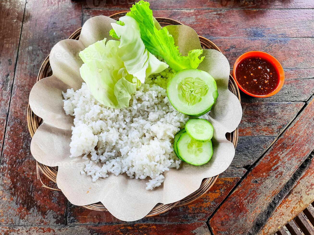 The traditional Indonesian food dish is called Ayam Penyet or fried chicken with rice and vegetables without chicken and tempeh photo