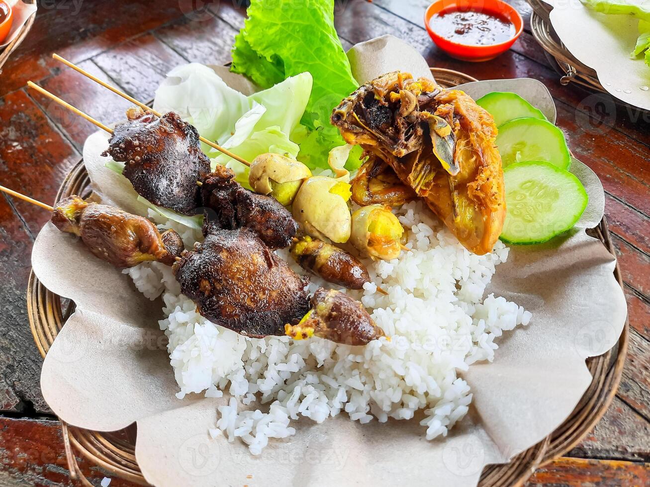 Traditional Indonesian food is called Ayam Penyet or fried chicken with rice and tempeh plus vegetables with chili sauce photo